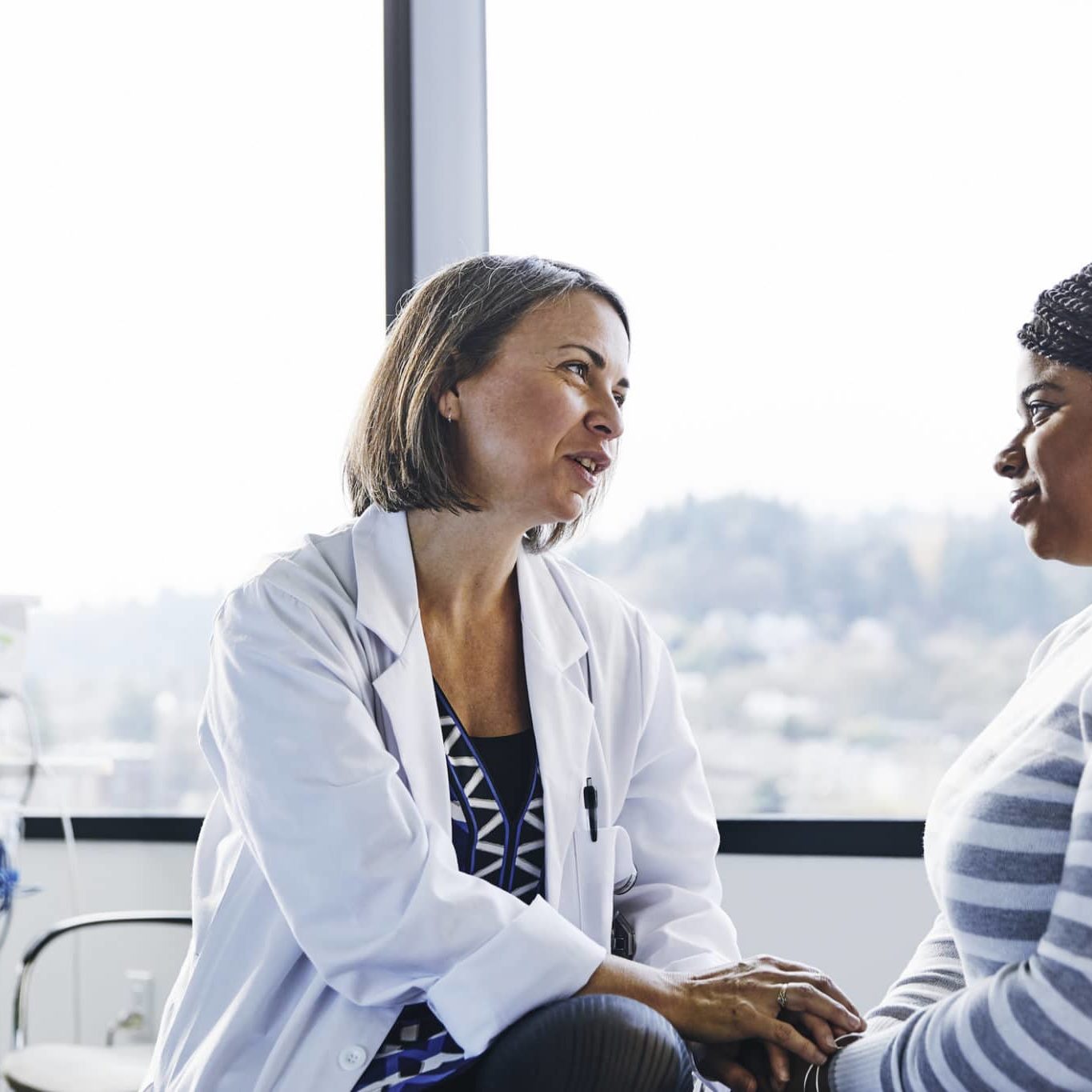 Smiling Doctor Talking To Young Woman In Hospital