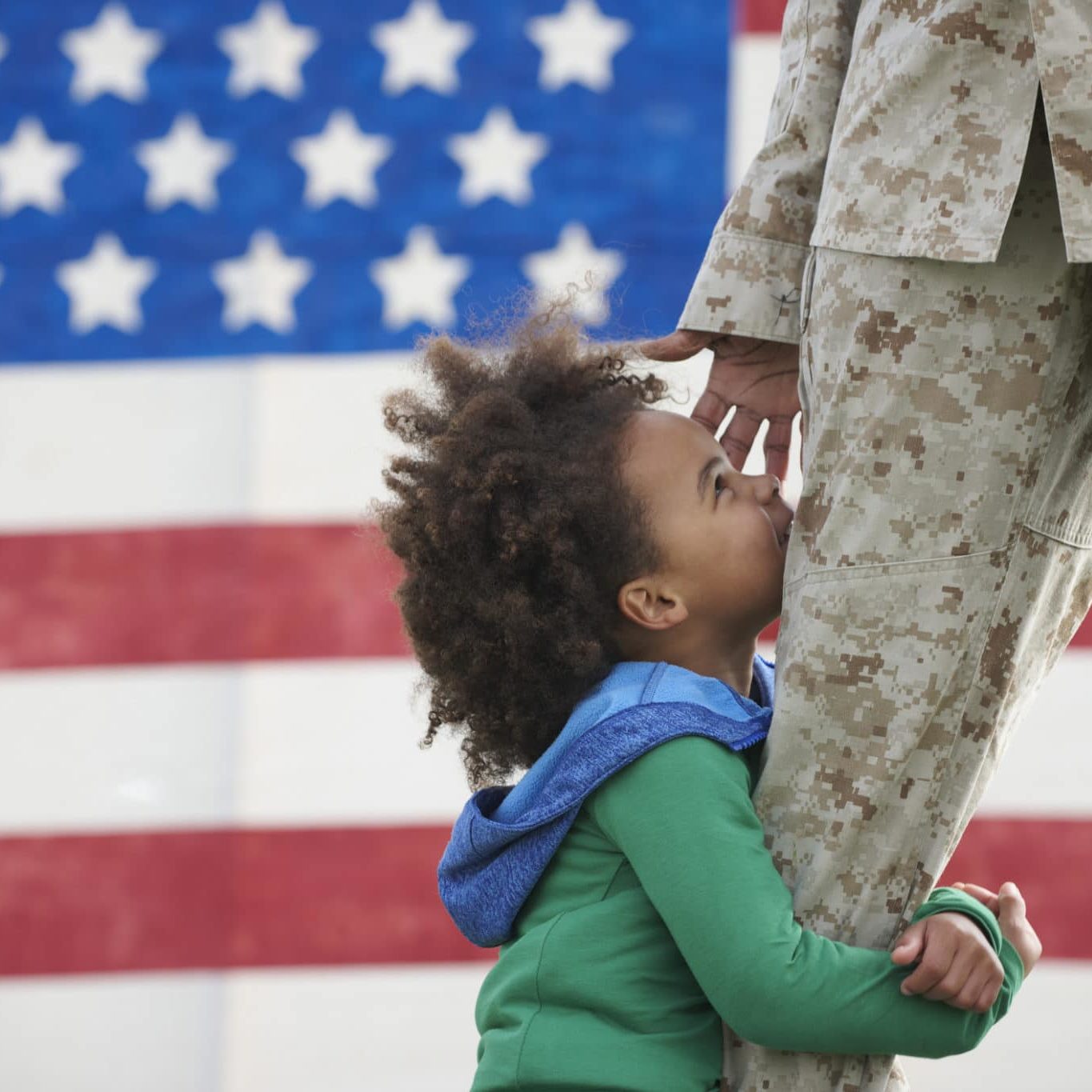 Black girl hugging leg of returning soldier
